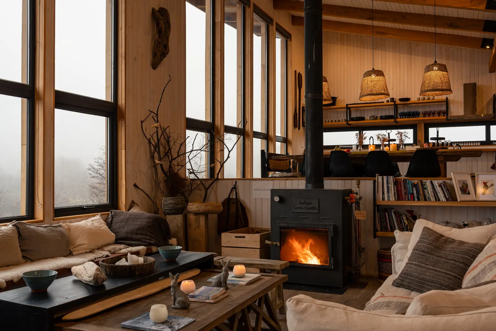 Living del lodge con chimenea y grandes ventanales