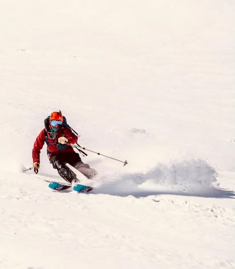 Esquiador descendiendo sobre nieve virgen